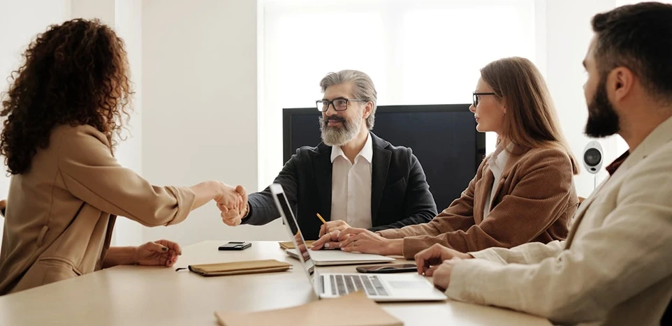 Frau und Mann schütteln Hände im Rahmen eines Recruiting-Meetings